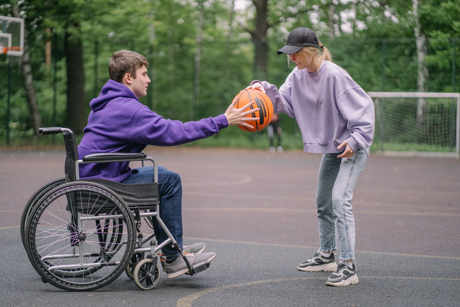 A support worker and a young man in a wheelchair playing basketball